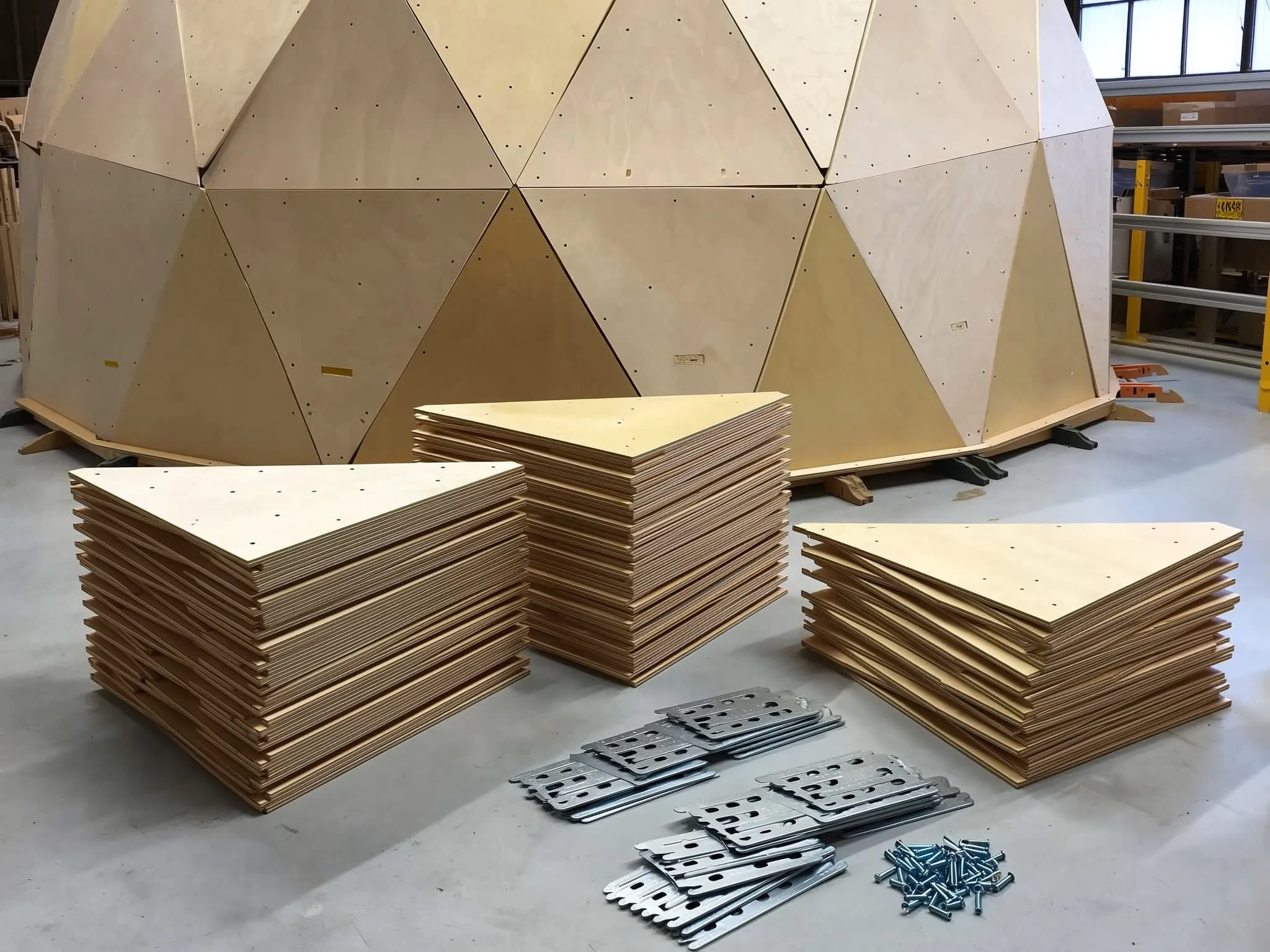 Kit de painéis triangulares em madeira, empilhados na oficina com os ligadores metálicos