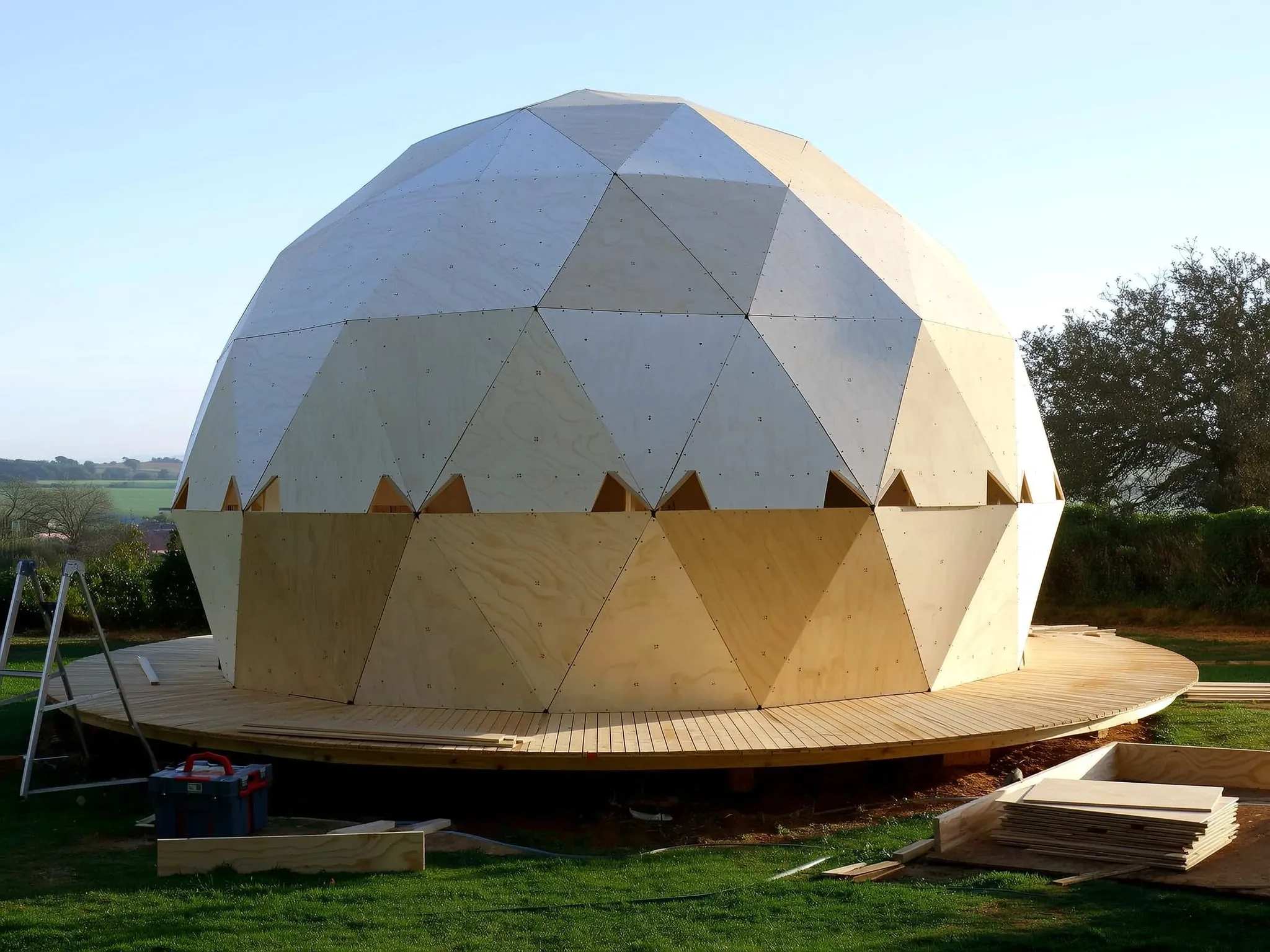 Cúpula de painéis triangulares em madeira em montagem, sobre uma plataforma de madeira